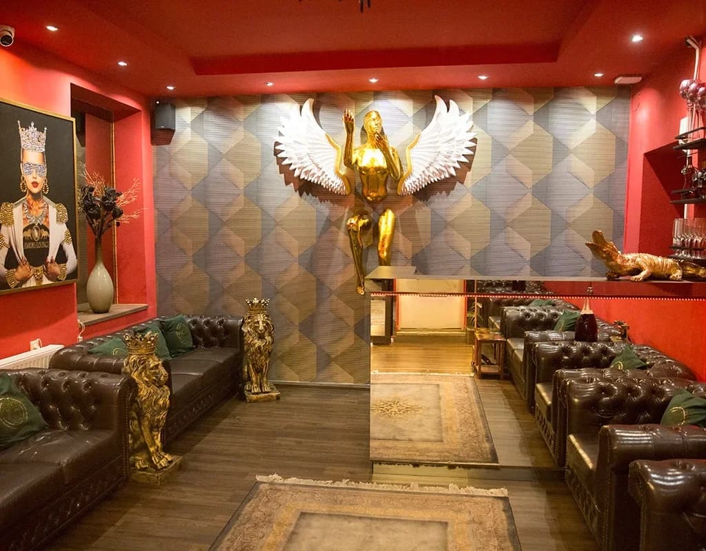 Lounge des Studio Amore 63 in Wien mit Chesterfield-Sofas und goldenen Skulpturen