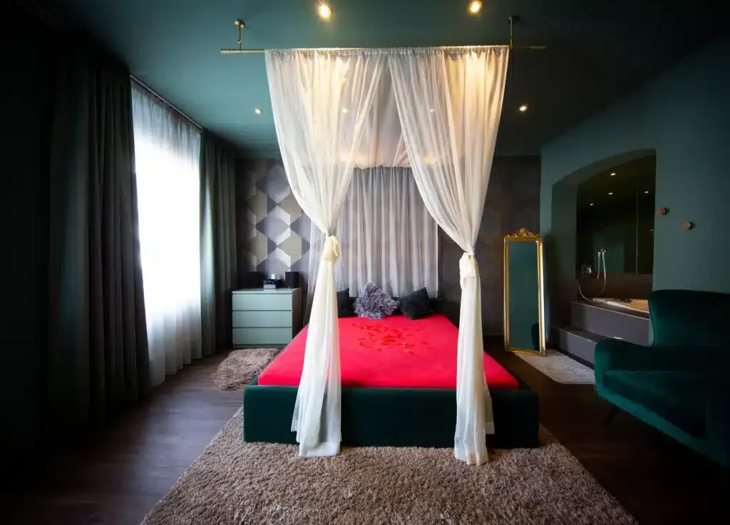 Zimmer mit Himmelbett und roter Bettwäsche im Studio Amore 63 in Wien